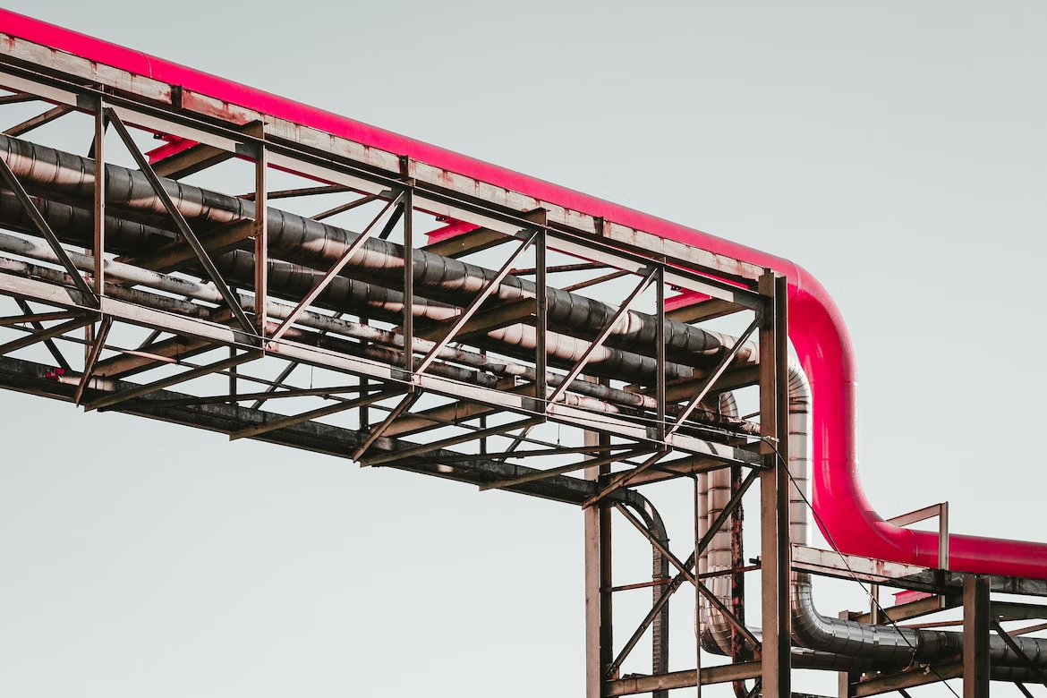 Industrial pipeline system on elevated steel structure with insulated piping and red protective coating